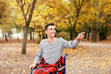 Handicapped young man pointing at something in autumn park