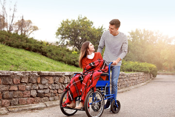 Handicapped young woman and her husband in autumn park