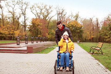 Handicapped young woman and her husband in autumn park