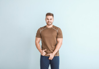 Young man with healthy urogenital system showing thumb-up on light background
