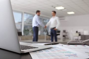 Workplace of bank manager and businessmen shaking hands in office