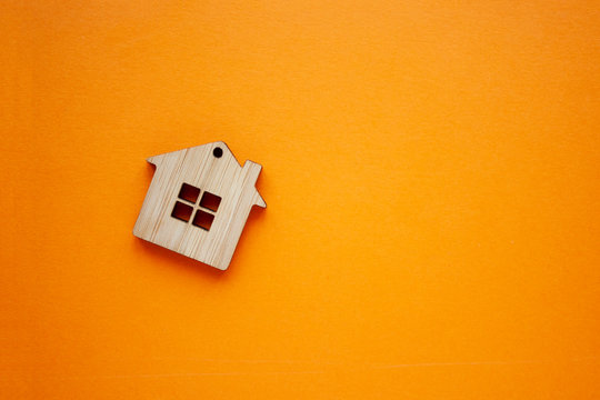 House, insurance and mortgage, buing and rent concept. Small wooden house toy on orange background top view copyspace