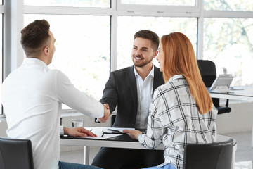 Bank manager and clients shaking hands in office