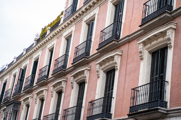 Fototapeta na wymiar Beautiful building with pink facade and balconies in Madrid Spain