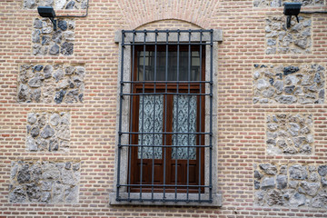 Fototapeta na wymiar Interesting window and wall brick facade with bars on window in Madrid Spain