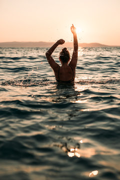 Girl in the Ocean splashing water during sunset