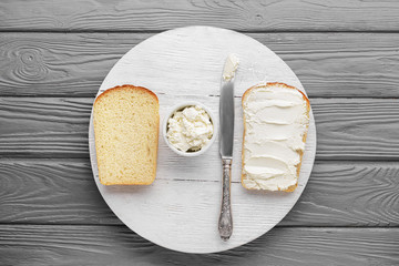 Slices of tasty bread with cream cheese on wooden background