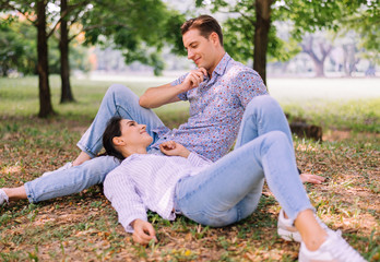 Obraz premium Couple young lover lying down on green grass in park together,Romantic and enjoying in moment of happiness time,Happy and smiling,Positive thinking,Eyes contact