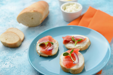 Sandwiches with tasty cream cheese and salmon on color background
