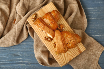 Board with tasty sweet croissant on wooden table
