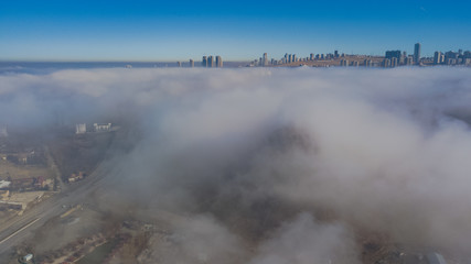 Plakat Landscape over the clouds in foggy weather. Hills of buildings in foggy weather. The drone and the top of the fog layer. Buildings in the fog.