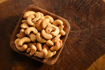 Cashews in a wooden bowl, on the wood background