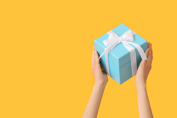Female hands with beautiful gift box on color background