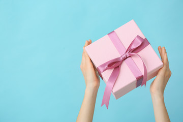 Female hands with beautiful gift box on color background