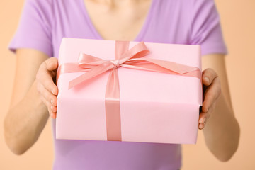Woman with with beautiful gift box on color background, closeup
