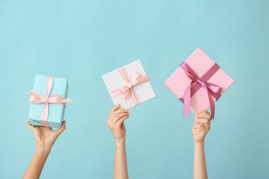 Female hands with beautiful gift boxes on color background