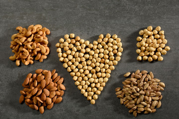 Nuts for heart health, heart shape hazelnuts and group of pistachios, almonds, cashews