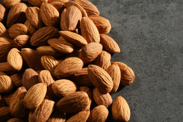 Heap of Almonds on the gray stone texture with copy space