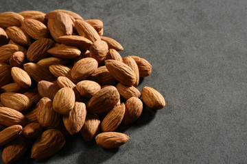 Heap of Almonds on the gray stone texture with copy space