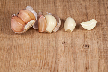 Stages of peeling garlic. A few cloves of garlic lie on a white oak kitchen board. Still life for the kitchen in a minimalist style.