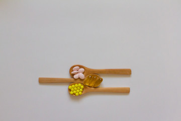 Assorted pharmaceutical medicine. Dosage. Tablets and capsules on a wooden spoon on a white background. Concept of medicine. Alternative homeopathy. Flatley. copyright of the text.