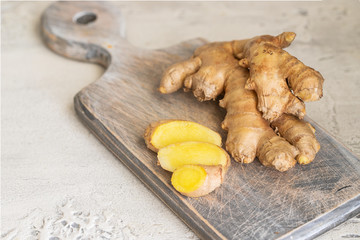 Ginger roots and ginger root sliced on cut board. Ginger used as spice for food and treatment in...