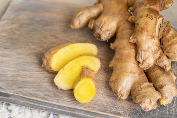 Ginger roots and ginger root sliced on cut board. Ginger used as spice for food and treatment in alternative medicine.