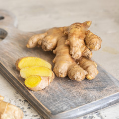 Ginger roots and ginger root sliced on cut board. Ginger used as spice for food and treatment in...