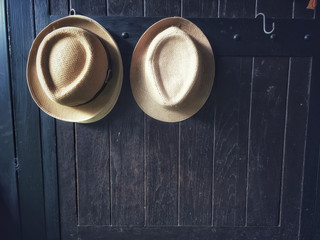 Two hats hanging dark brown wooden doors