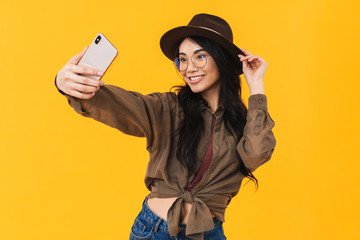 Image of young brunette asian woman taking selfie photo on cellphone