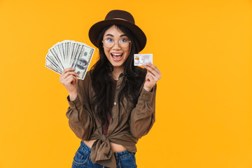 Image of young asian woman holding money banknotes and credit card