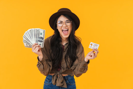 Image of young asian woman holding money banknotes and credit card
