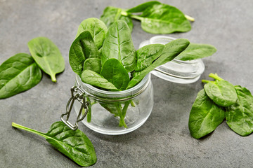Fresh green spinach leaves in glass bowl on gray table. Organic food, healthy diet, vegetarian food. Top view. Close up.