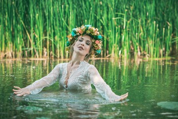 Romantic woman in flower hoop at hair, lace transparent dress in lake 