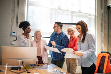 Young happy entrepreneur talking to his colleagues during a business meeting in a board room. Mid...