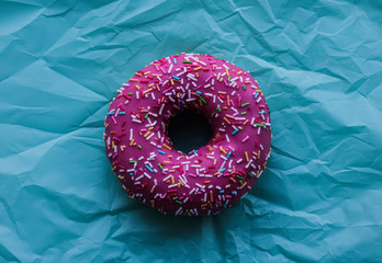 pink donut with colored sprinkles on a blue background
