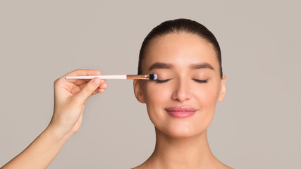 Makeup artist applying eyeshadows on female model face