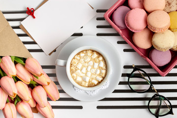 Top view of cup of marshmallows with tulips and macarons