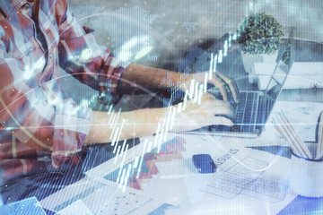 Double exposure of stock graph with businessman typing on computer in office on background. Concept of hard work.