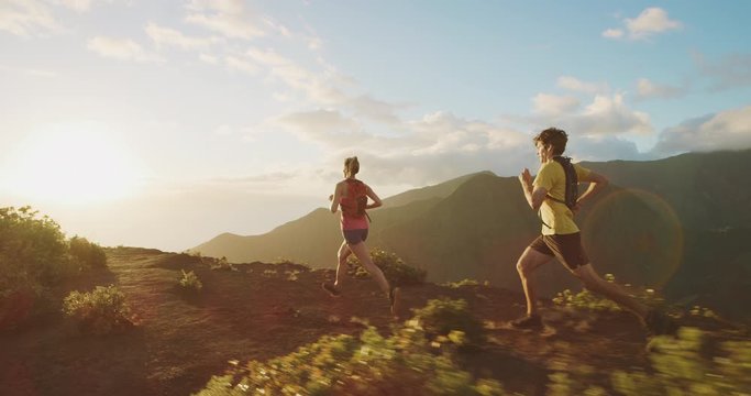 Young athletic friends running into the sunset on a mountain top together, outdoors exercise in amazing places