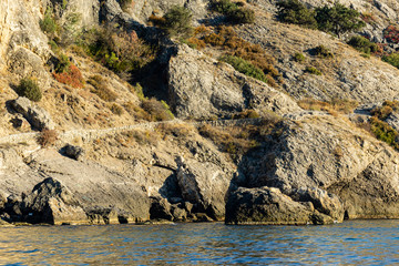 Cape Alchak on southern coast of Crimea on outskirts of resort town of Sudak. Closeup of huge stones and natural boulders. Fabulous view from Alchak-Kaya trail to impregnable mountain alongrocky shore