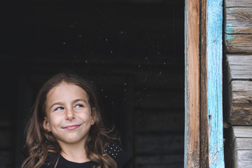 Fototapeta premium Children peep out the window of an old wooden house and smiling. Summer vacation in the country