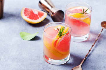 Grapefruit drink with rosemary on grey board.