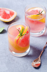 Grapefruit drink with rosemary on grey board.