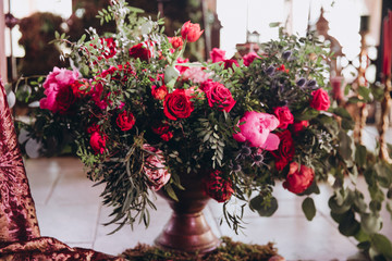 the festive hall is decorated with compositions of marsala flowers and greens in vases, candles and fabrics