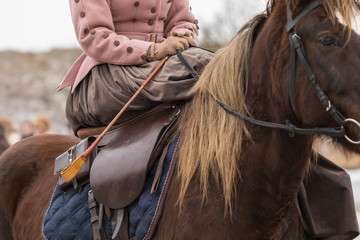 A horsewoman in a suit with a skirt sits riding a horse in a ladies 'saddle. The lady has a...