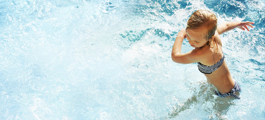 Fototapeta na wymiar Little girl having fun time in the Swimming pool, Summer time, Vacation