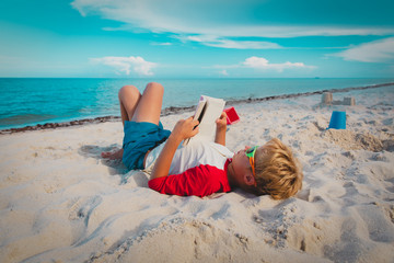boy reading book at sand beach, kid learning on vacation
