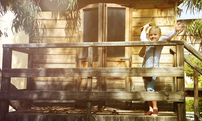 Fototapeta na wymiar Little blond girl enjoying summer vacation time at the tree house. Gardening
