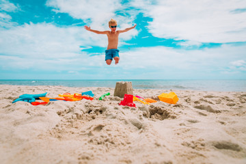 Fototapeta na wymiar toys on sand beach and happy boy enjoy tropical vacation